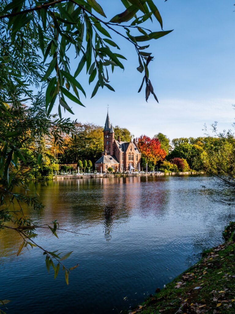 Photo of bruges, a beautiful building can be seen from across the river.